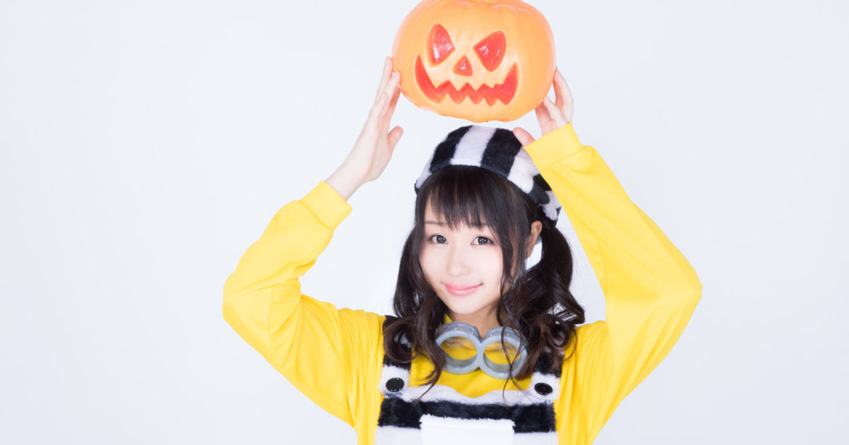 ハロウィンのかぼちゃお化けを持ち上げる仮装女子