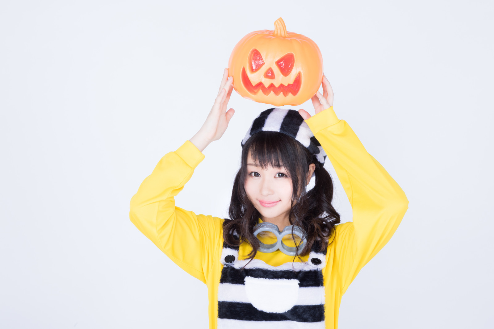 ハロウィンのかぼちゃお化けを持ち上げる仮装女子