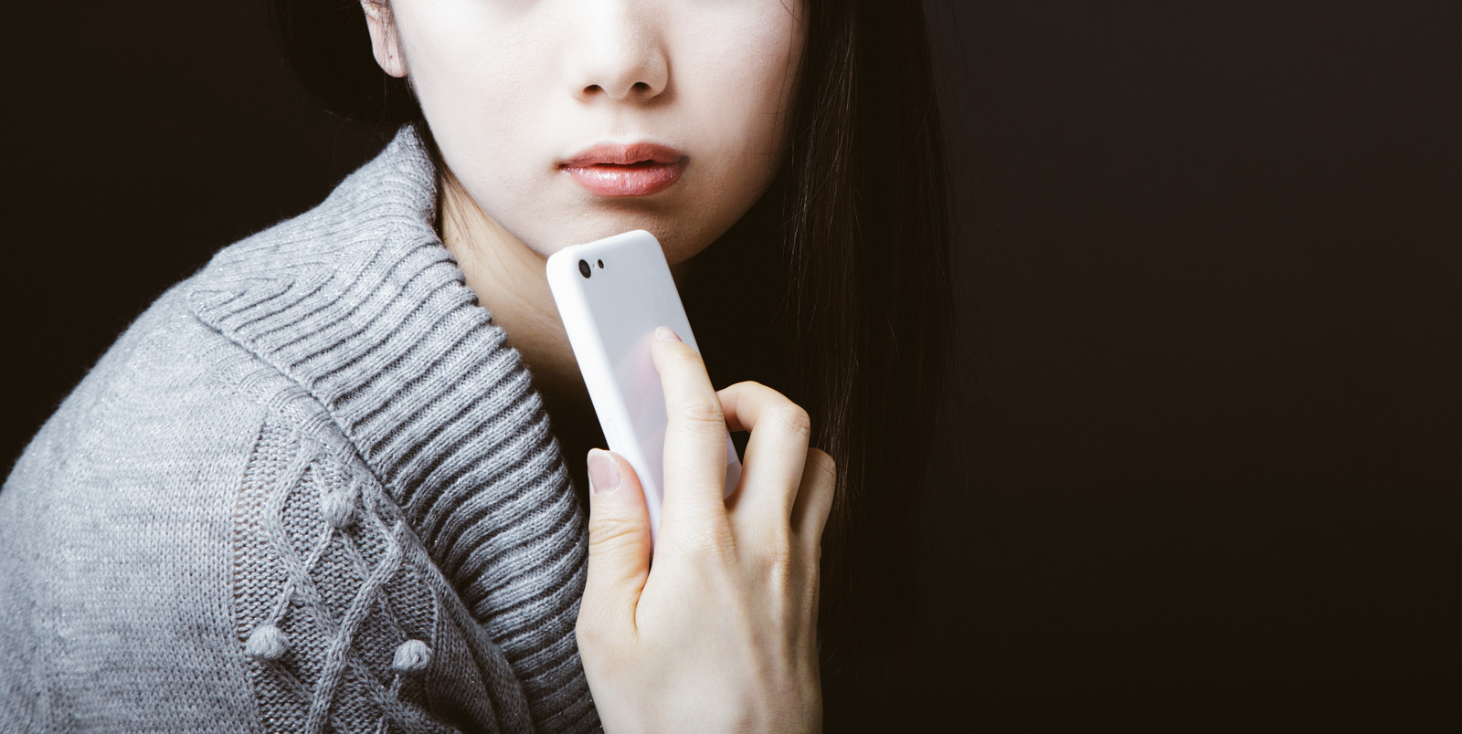 スマホを顎にあてて考える女性