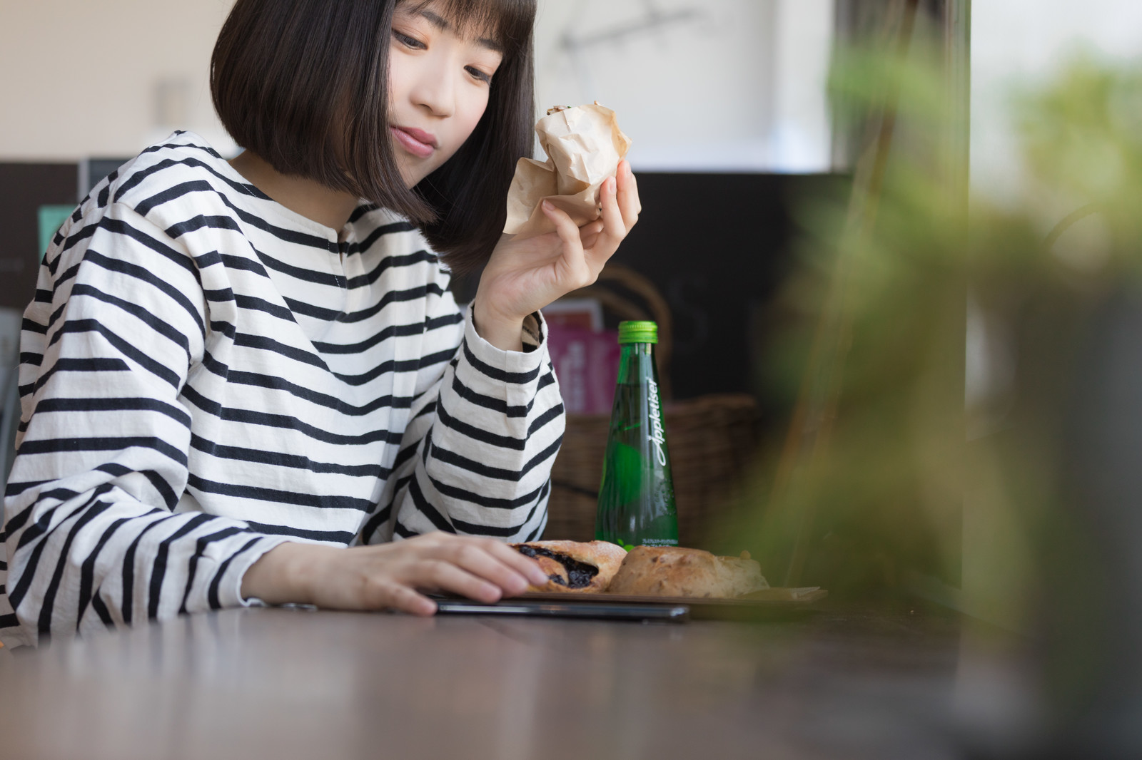 パンを食べながらスマホで売上をチェックする女性