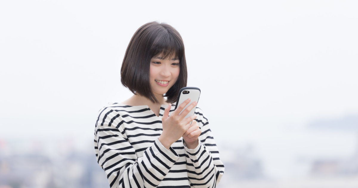 スマホで10大ニュースと重大発表をみる女性