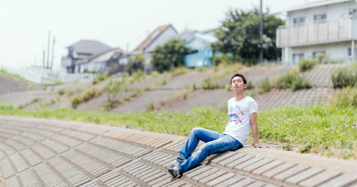 土手で日向ぼっこ中のフリーランスの男性