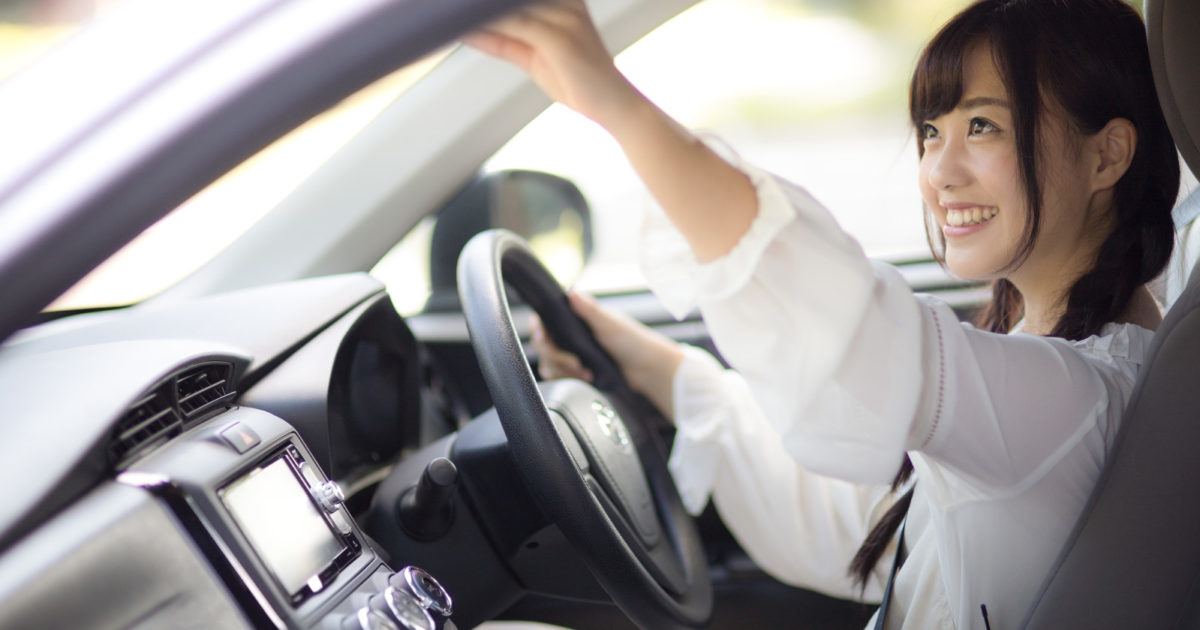 車内のバックミラーを調整する女子