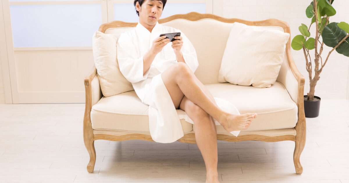 脱毛サロンでスマホで記事を更新する男性