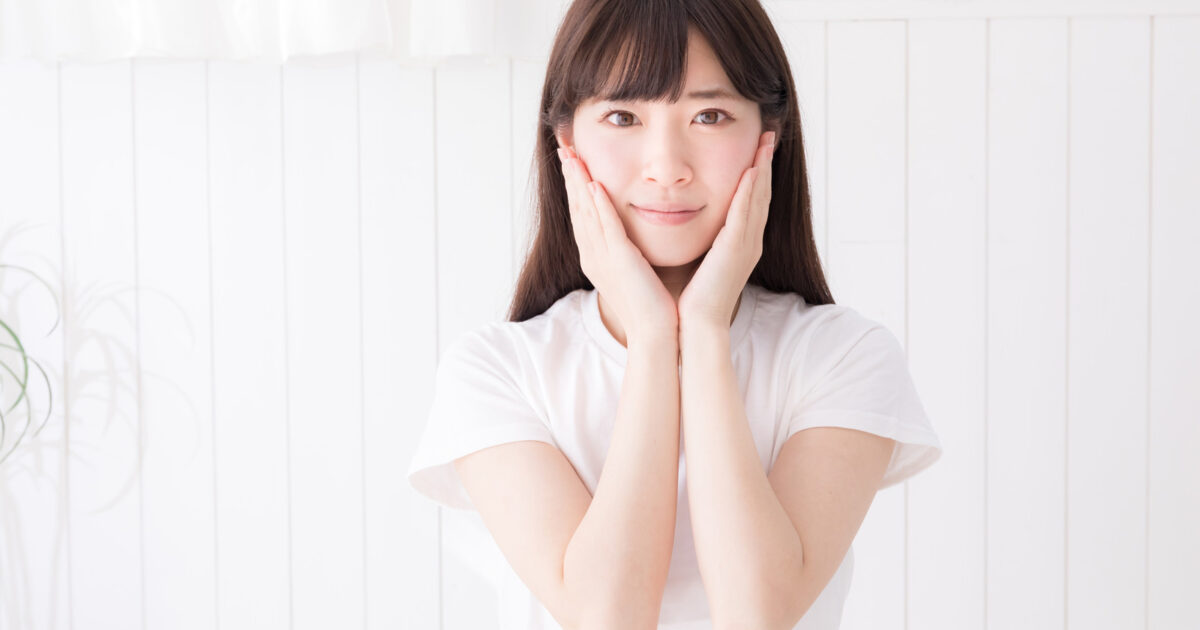 両手を頬の横で合わせる女性